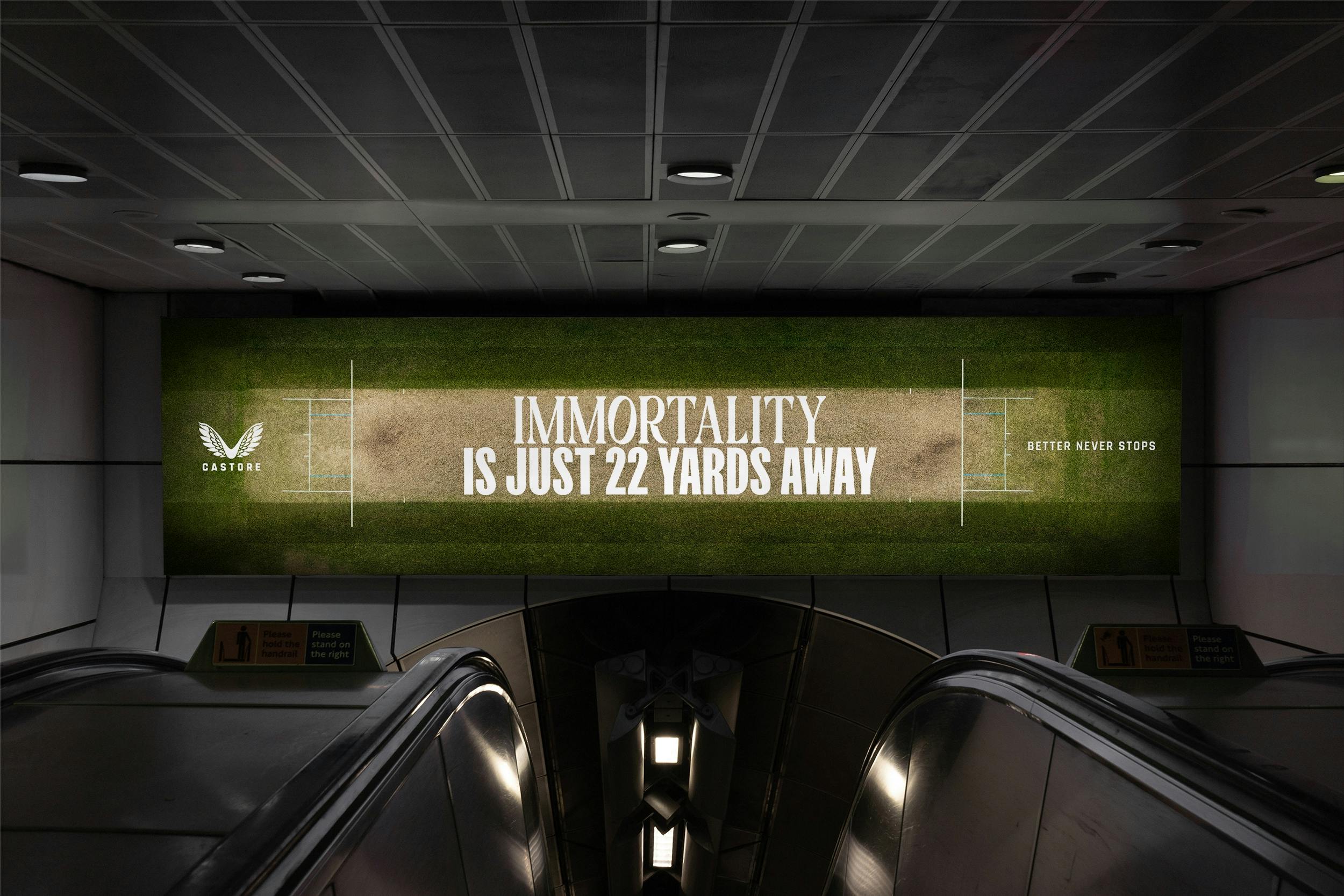 An advertisement above an escalator in the London Underground. The advert is a top down shot of a cricket wicket with the text top "Immortality is just 22 yards away".