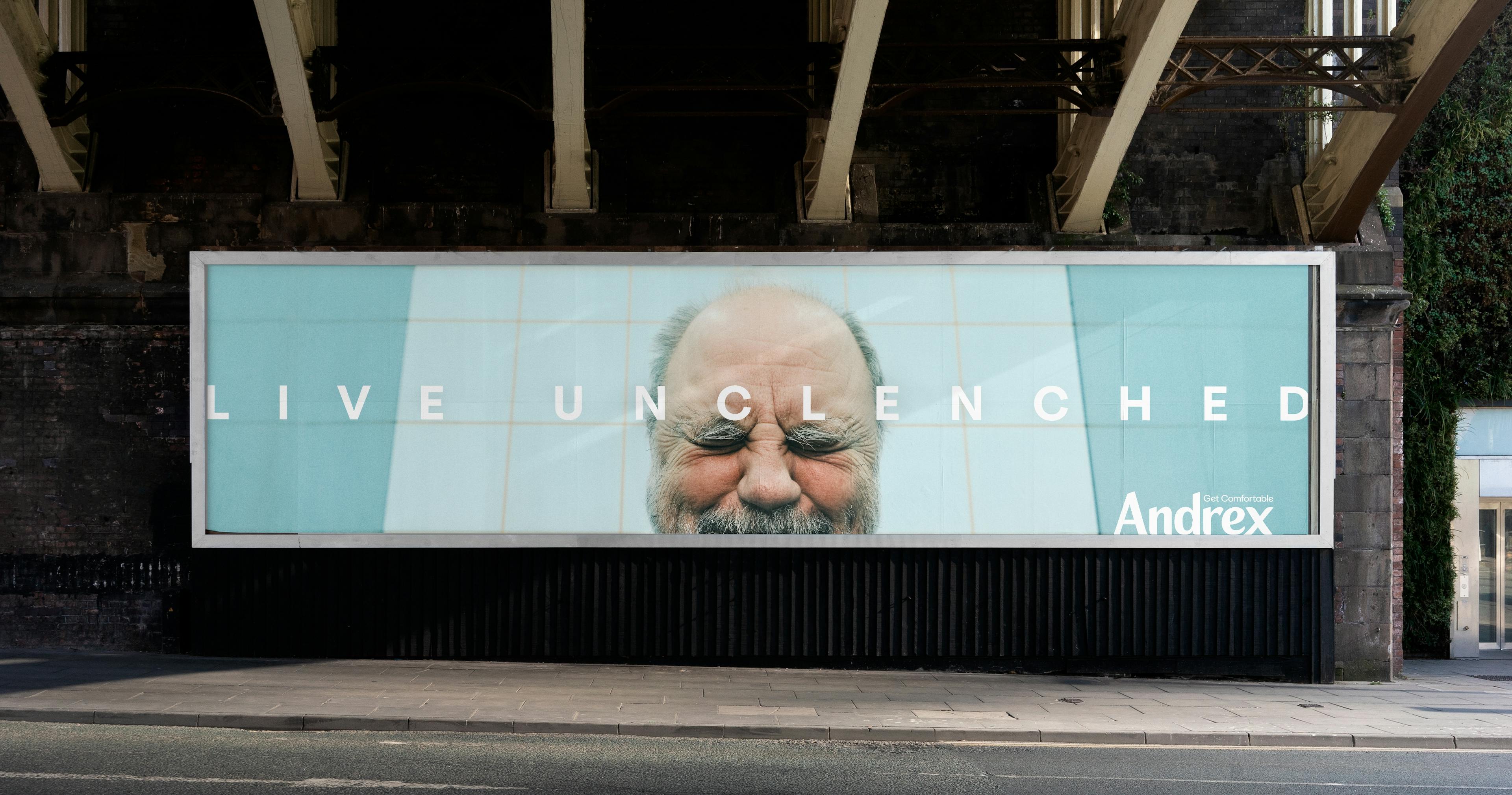 Billboard advertisement featuring a close-up image of a man's smiling face with eyes closed, accompanied by the slogan "Live Unclenched" and the Andrex brand logo.